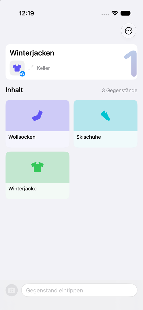 Geöffnete Kiste „Winterjacken“ im Keller mit drei Gegenstandskacheln: Wollsocken, Skischuhe, Winterjacke.